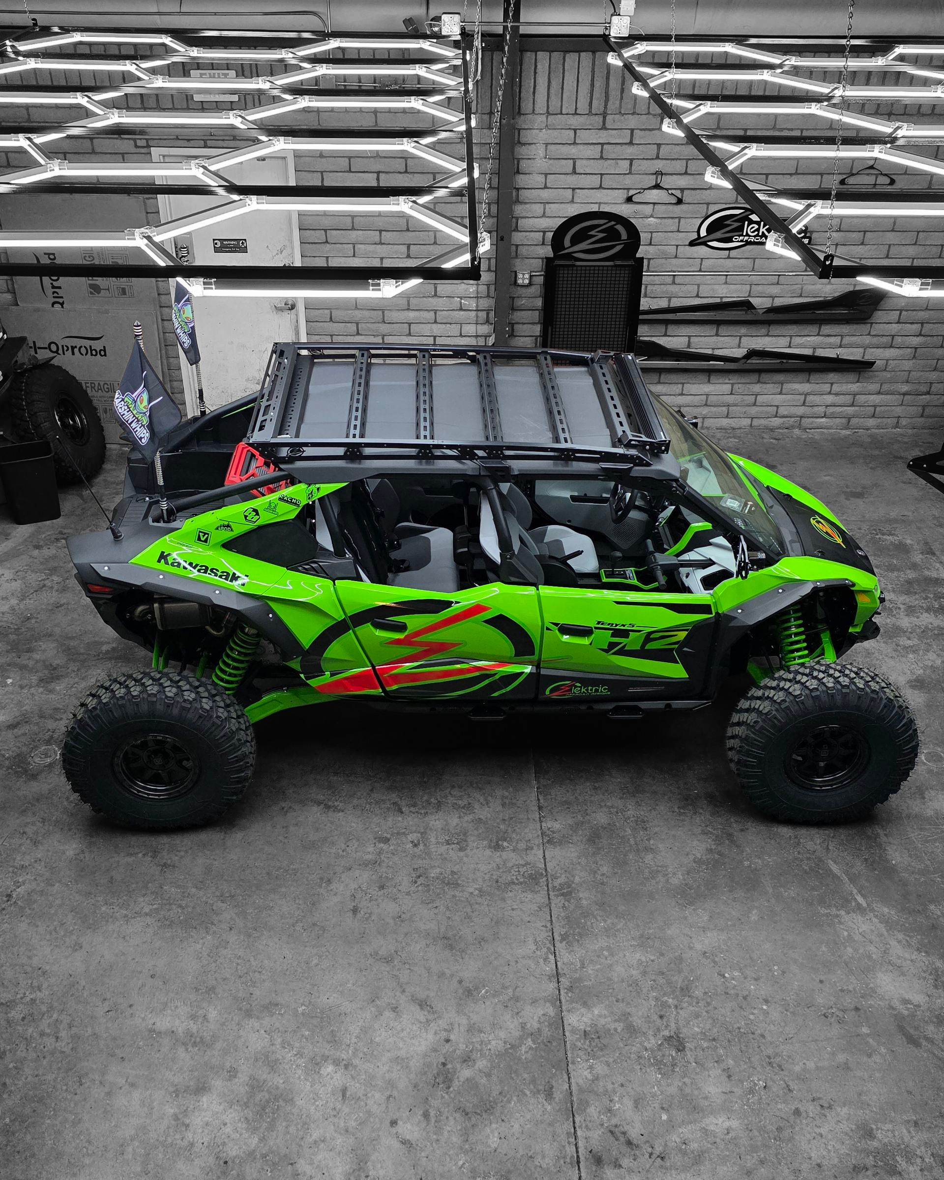 Green off-road vehicle with large tires in a garage setting